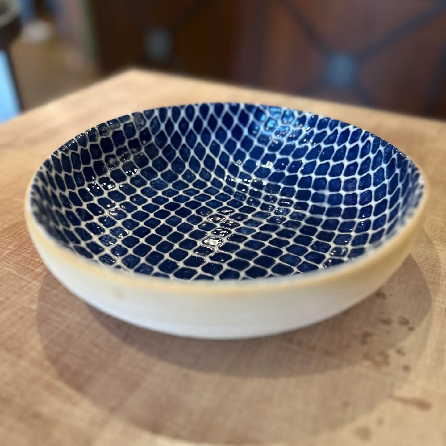 Ceramic bowl with blue mosaic pattern on a wooden surface