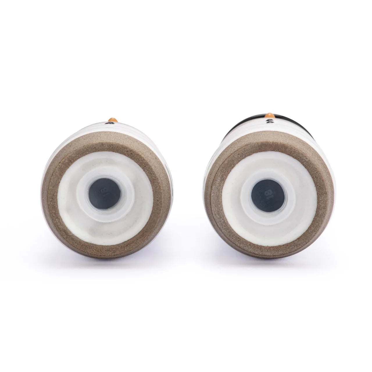 Bottom view of two white ceramic spice grinders with cork rings on white background