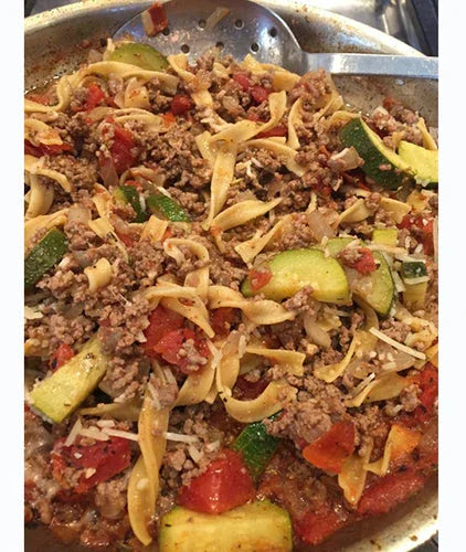 Skillet of cheesy beef pasta with ground meat, zucchini, tomatoes, and melted cheese