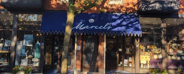 Marcel's boutique exterior with navy blue awning, brick facade, and display windows showcasing dresses and decorative items