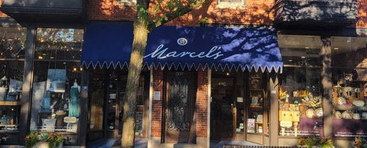 Marcel's boutique exterior with navy blue awning, brick facade, and display windows showcasing dresses and decorative items