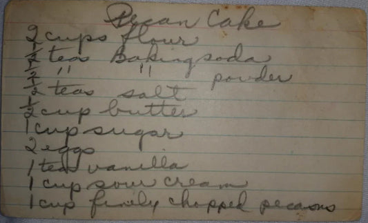 Handwritten vintage recipe card for pecan cake with ingredients like flour, baking soda, butter, sugar, eggs, vanilla, sour cream, and pecans