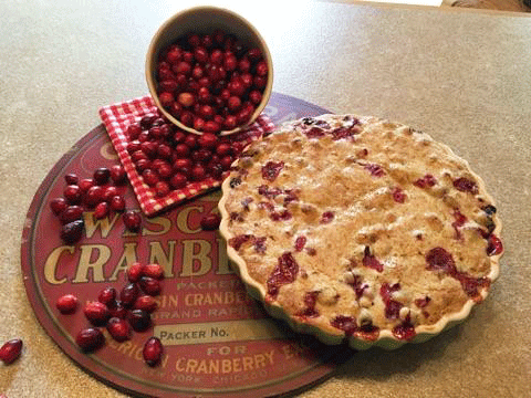 Fresh homemade cranberry tart on a round Wisconsin cranberry vintage tray with spilled fresh cranberries