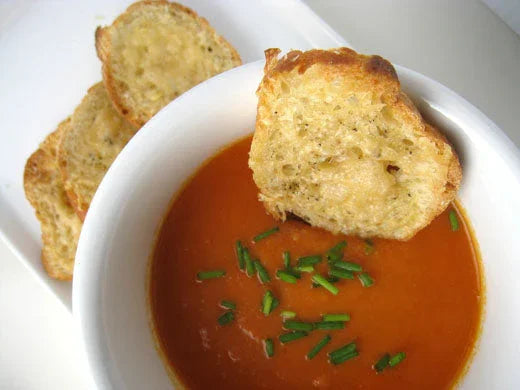 Creamy tomato soup garnished with chopped chives and served with toasted garlic bread