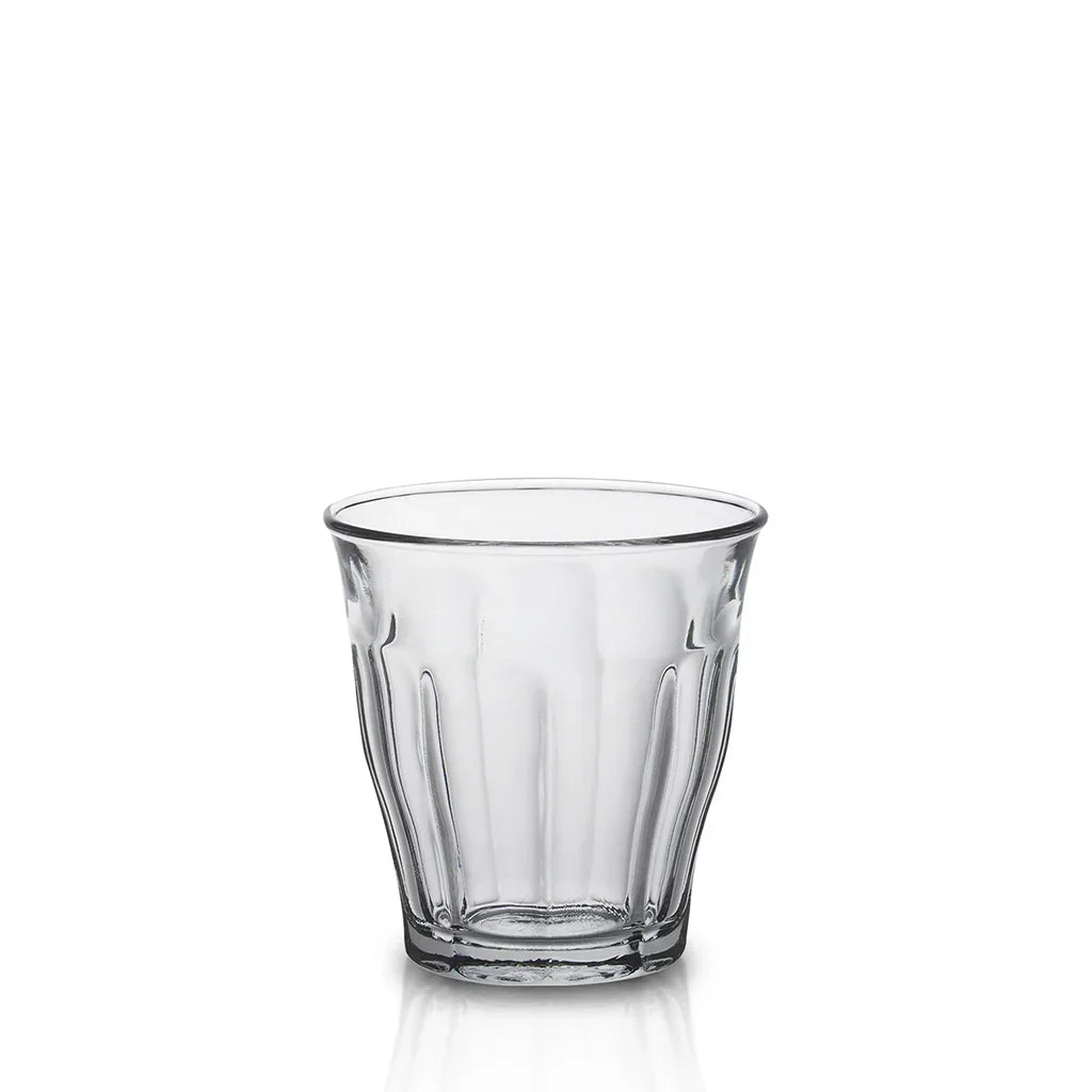 Empty clear ribbed glass tumbler with thick base on white background