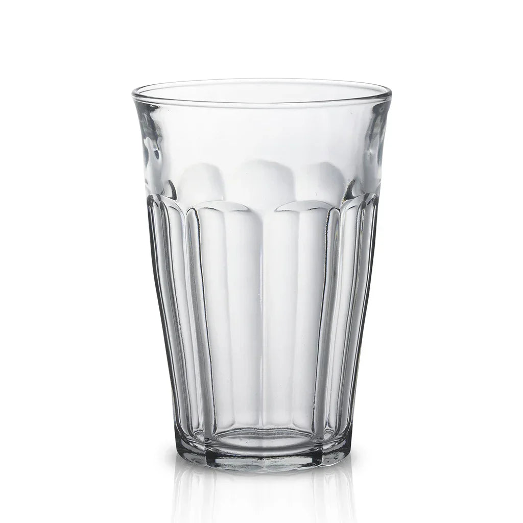 Clear faceted drinking glass with vertical ridges on white background