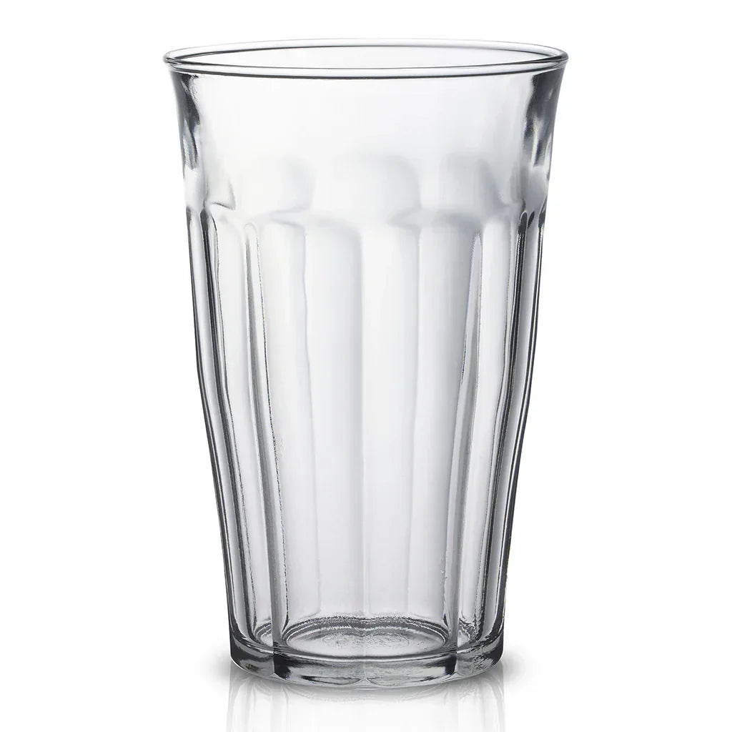 Clear empty textured drinking glass with vertical ridges on white background