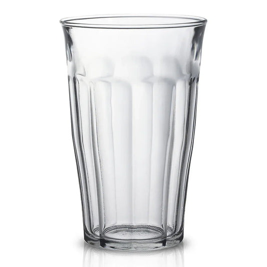 Clear empty textured drinking glass with vertical ridges on white background
