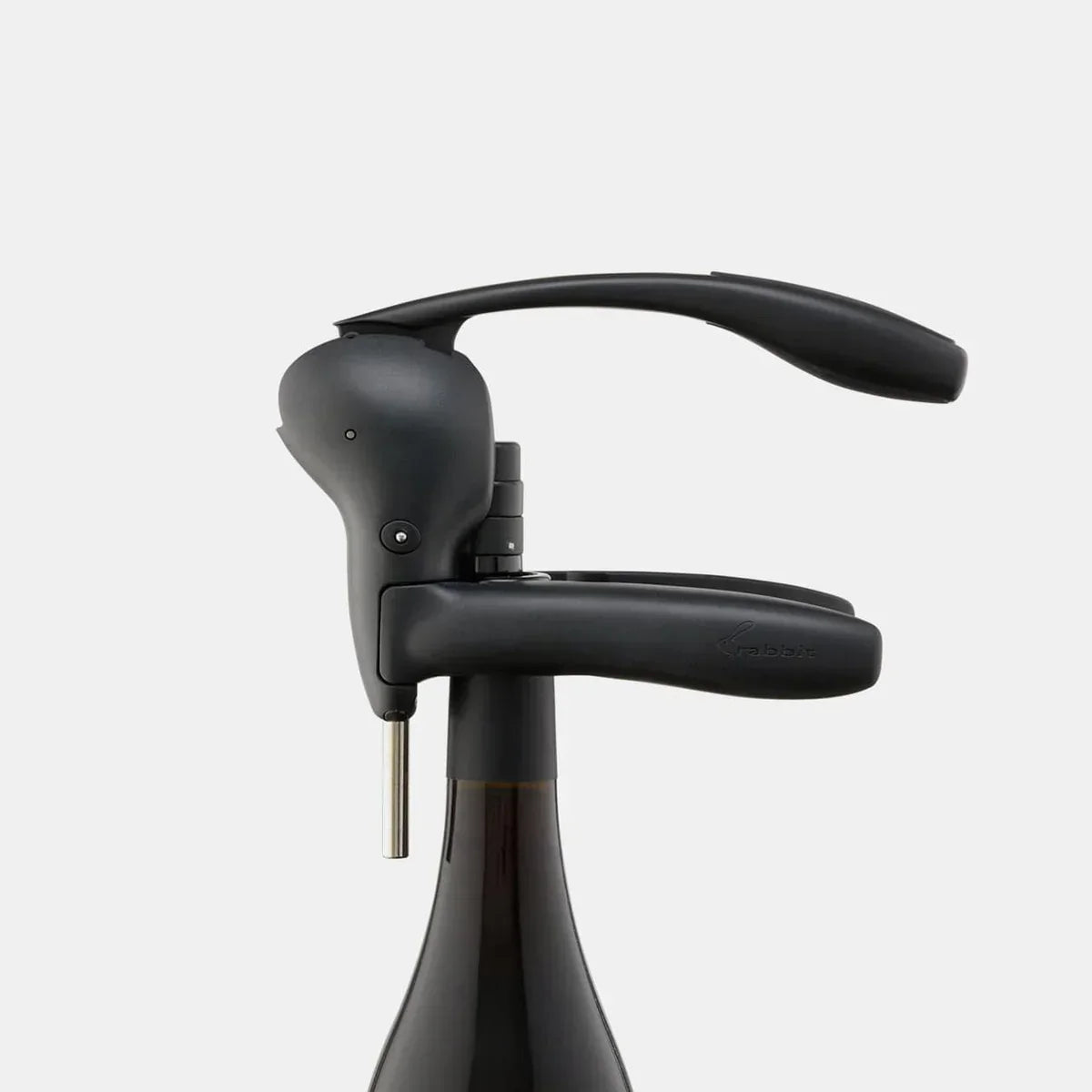 Black lever corkscrew on top of a dark wine bottle with ergonomic handle design