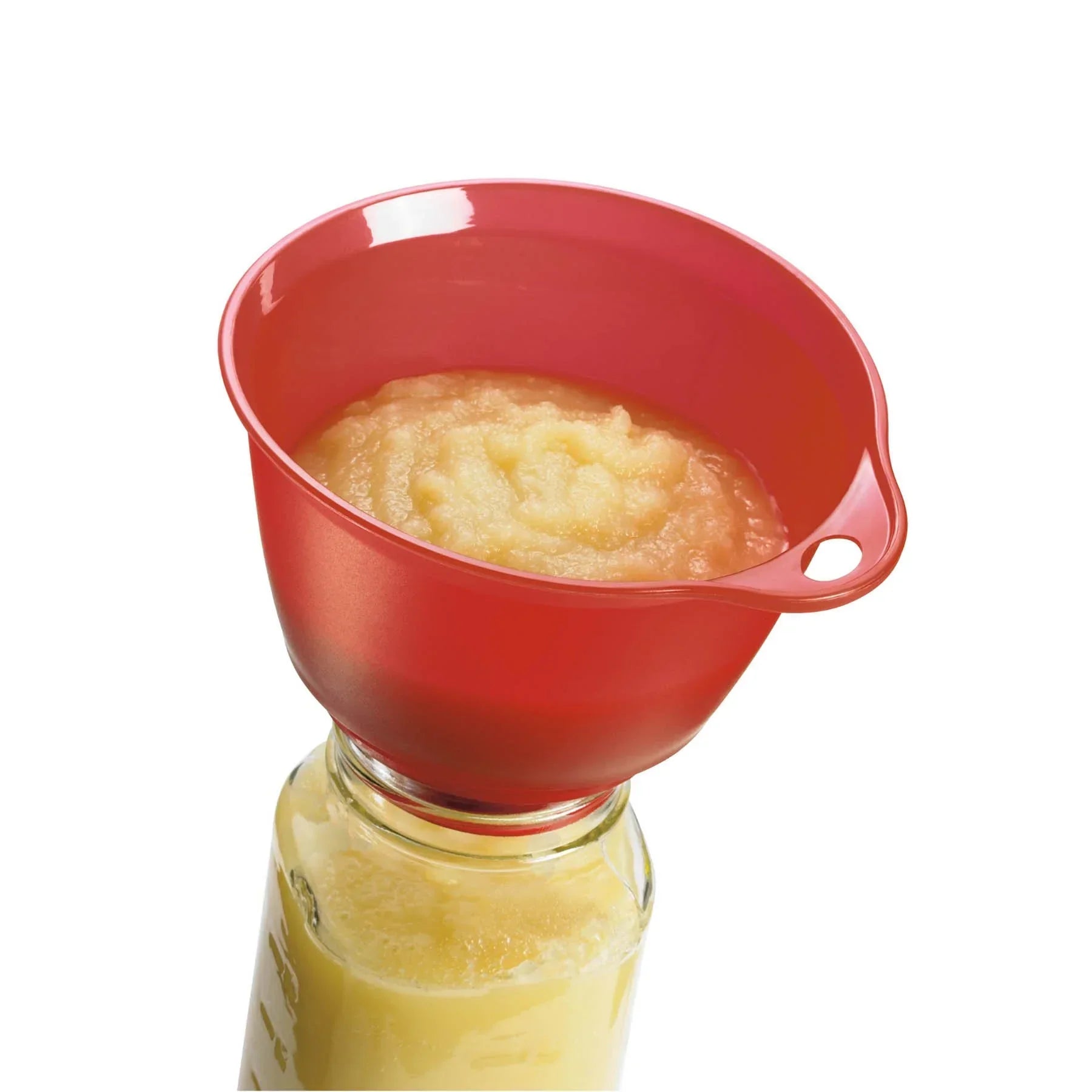 Red plastic funnel filled with applesauce over glass jar with yellow puree inside