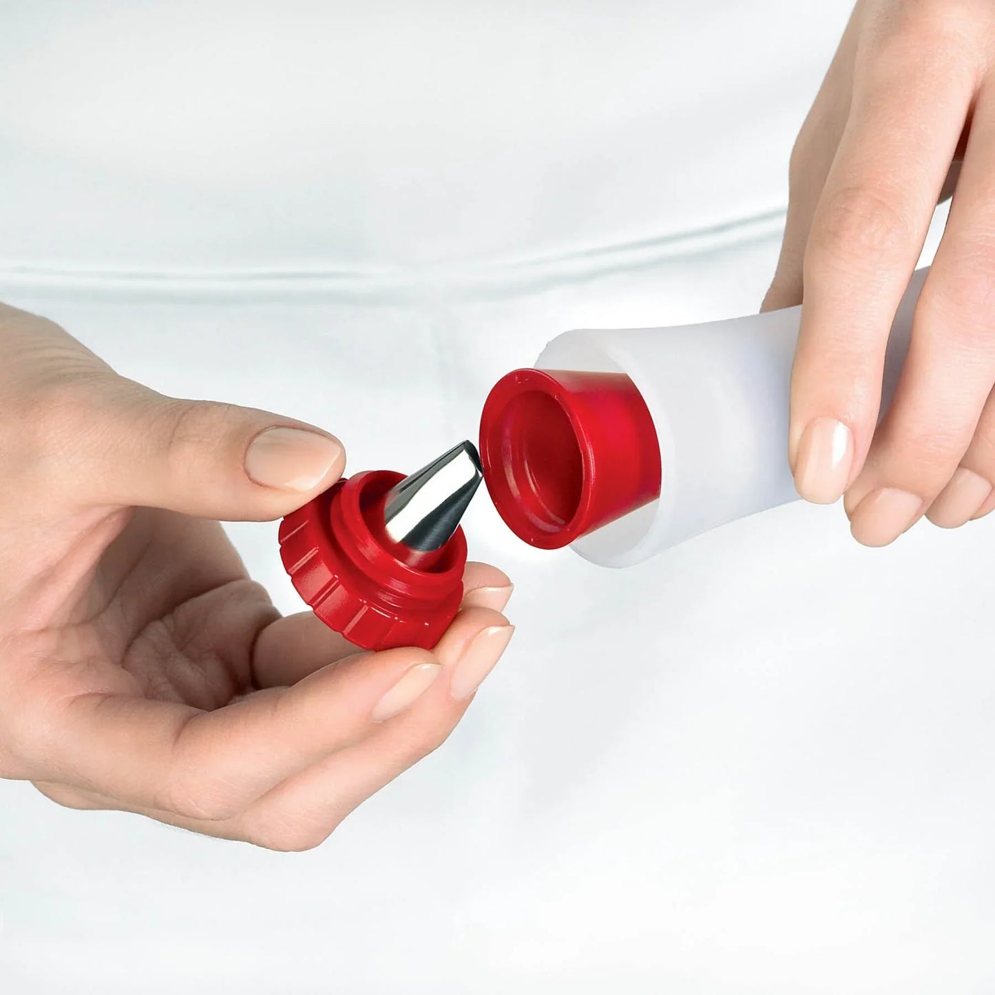 Hands holding an open white squeeze bottle with a red and silver nozzle cap