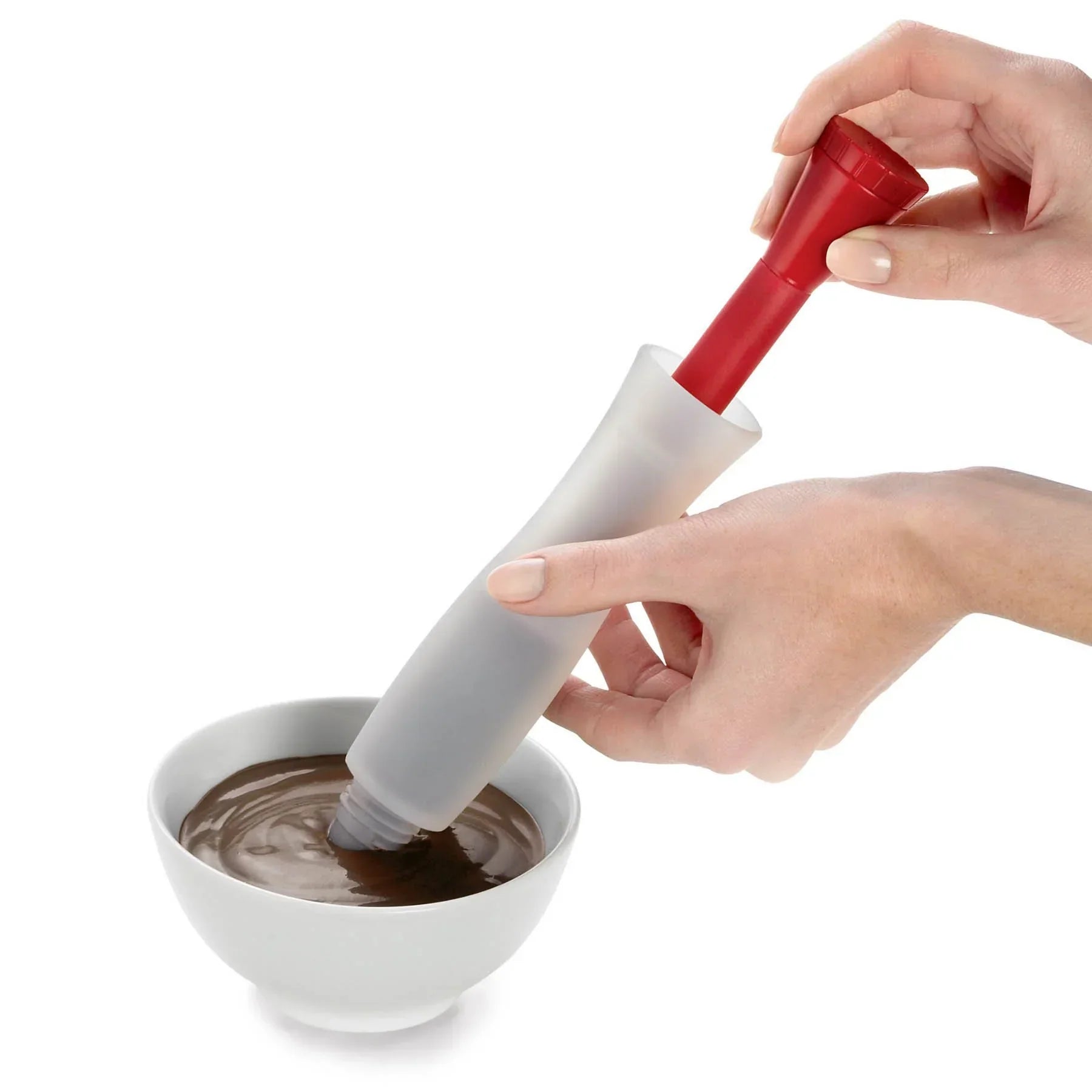 Hand using red and gray silicone tool to stir chocolate mousse in white bowl
