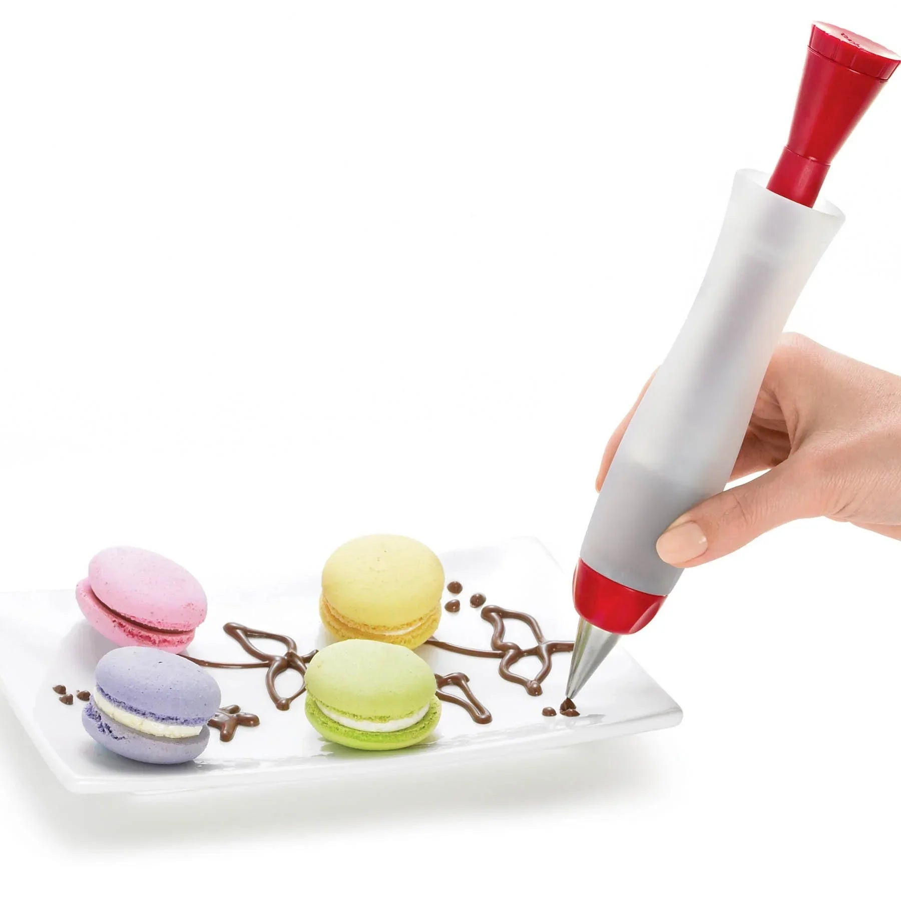 Hand decorating plate of colorful macarons with chocolate using a red and white icing pen