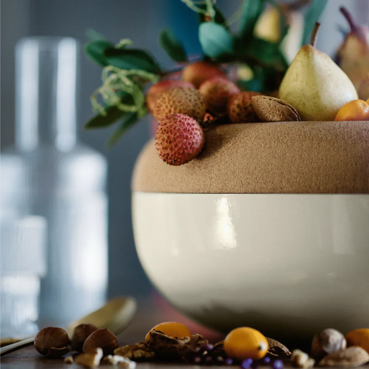 Large clay and ceramic storage bowl with fresh fruit including lychee, pear, and kumquats on table