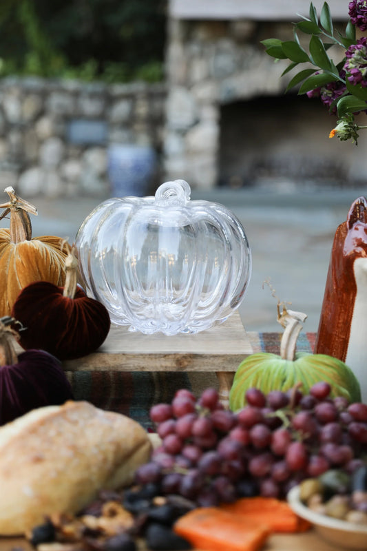 Clear glass pumpkin centerpiece on wooden stand with velvet pumpkins and autumn decor
