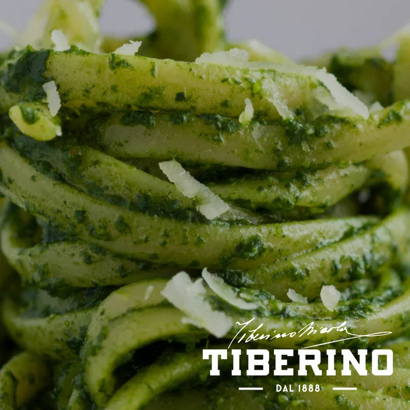 Close-up of linguine pasta coated with green Genovese pesto and topped with Parmesan shavings