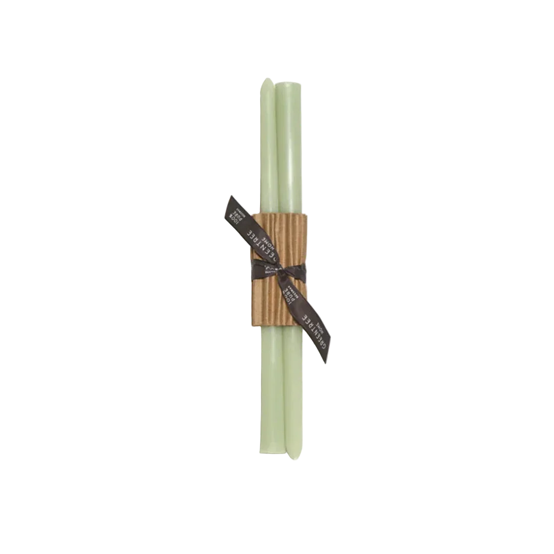 Two green candles tied with a brown ribbon on a white background