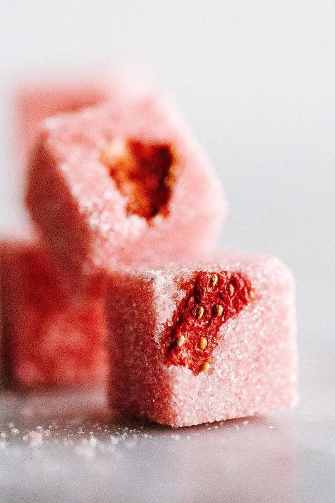 Close-up of pink sugar-coated strawberry Turkish delight cubes with visible strawberry pieces