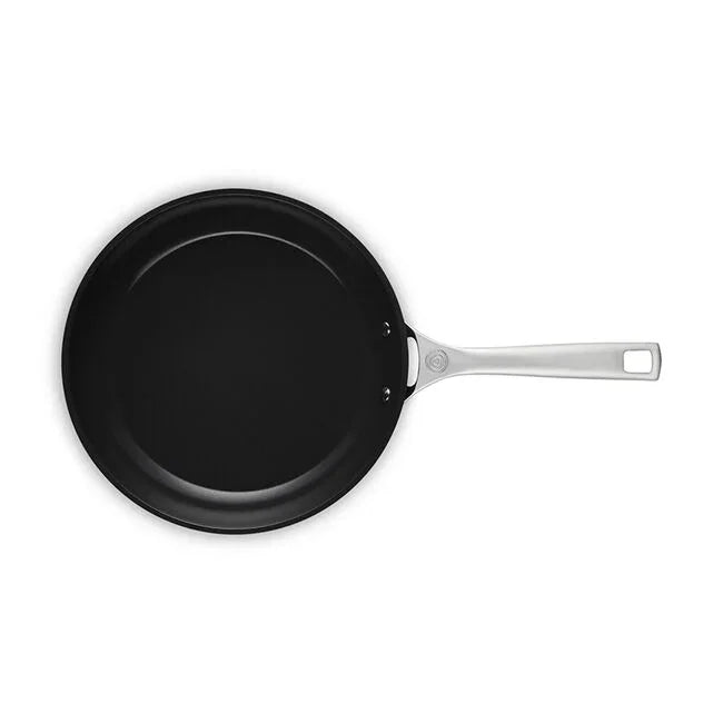Black ceramic nonstick frying pan with stainless steel handle on white background