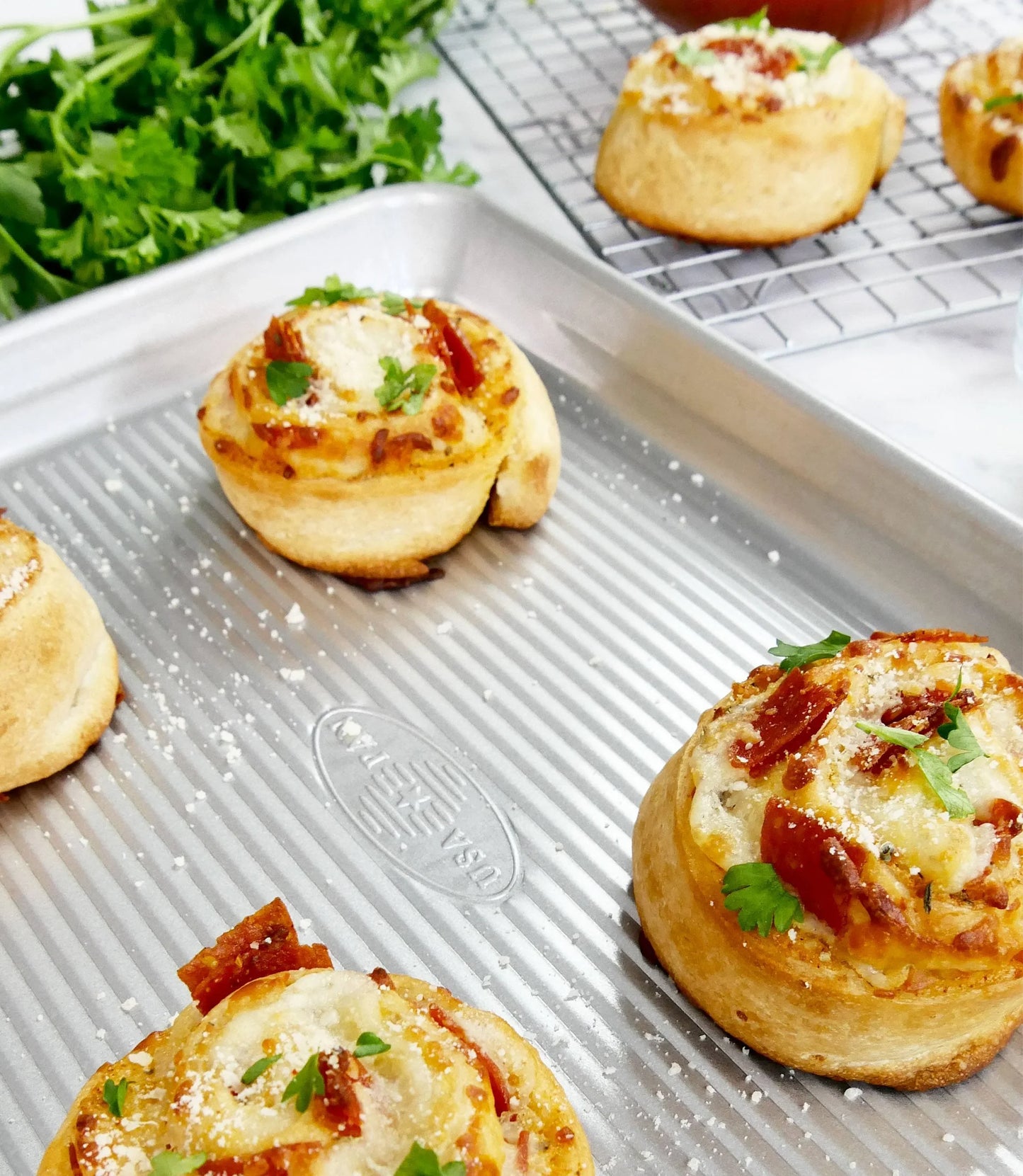 Freshly baked savory pizza rolls with melted cheese, pepperoni, and parsley on baking tray