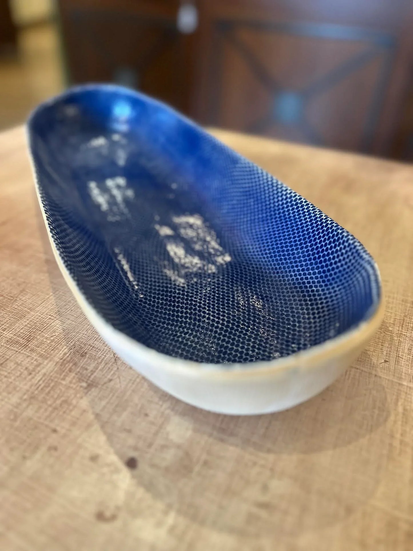 Close-up of empty elongated ceramic bowl with textured blue interior on wooden table