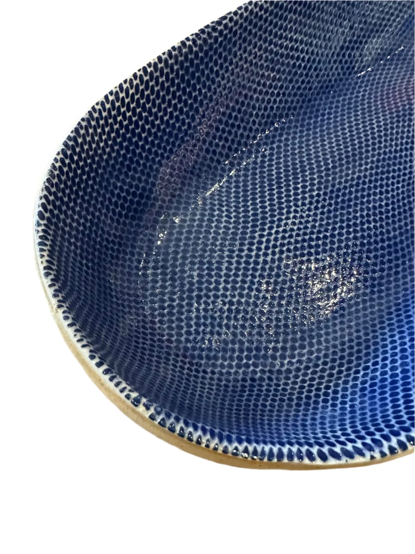 Close-up of a blue textured ceramic bowl with raised dot pattern and glossy finish