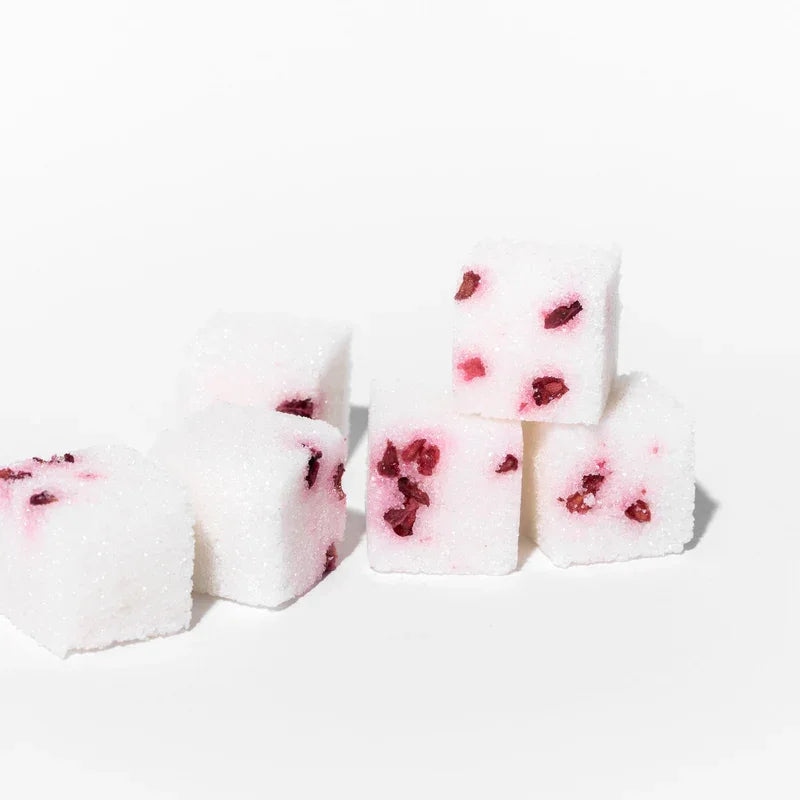 White sugar cubes with embedded red raspberry pieces on a white background