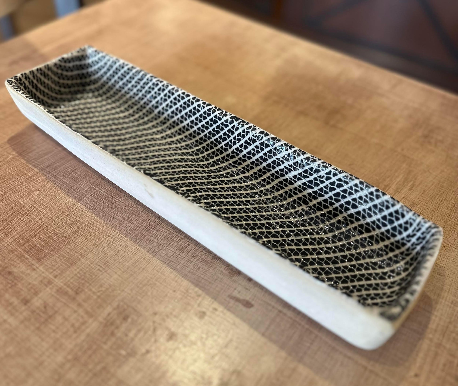 Rectangular black and white ceramic tray with geometric pattern on wooden table