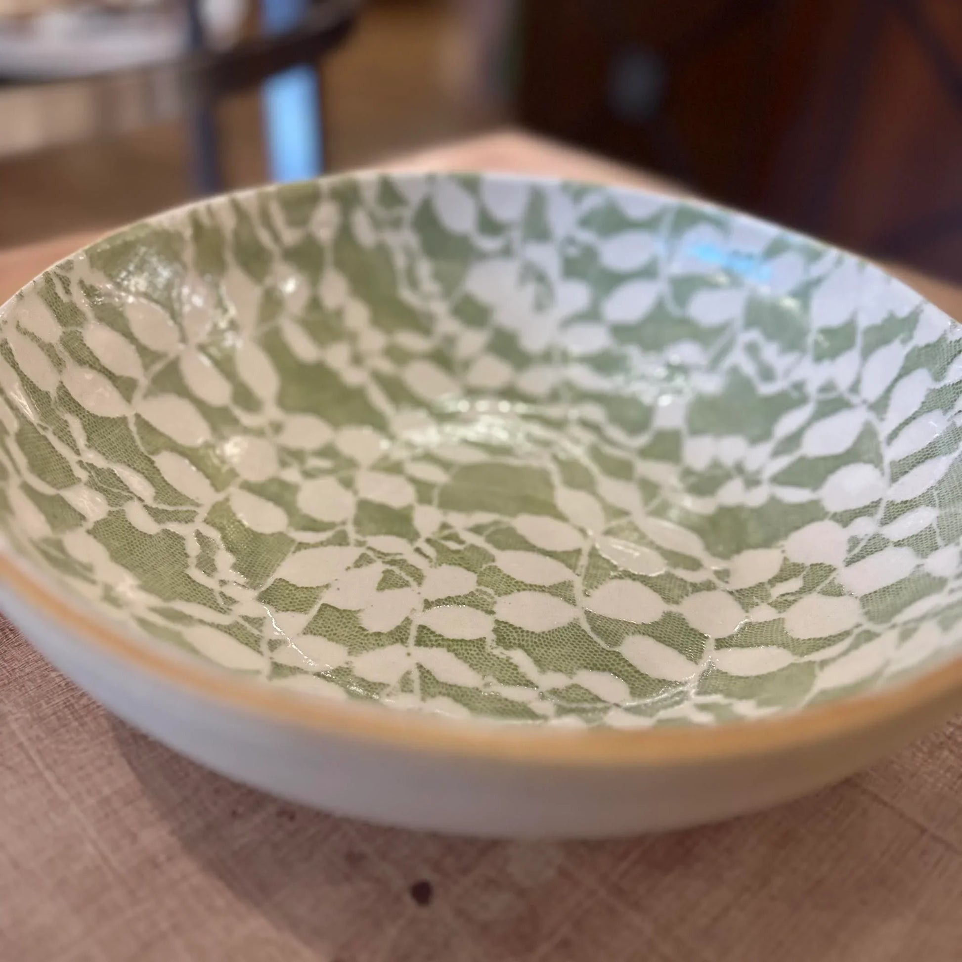 Ceramic bowl with green and white pattern on a wooden surface
