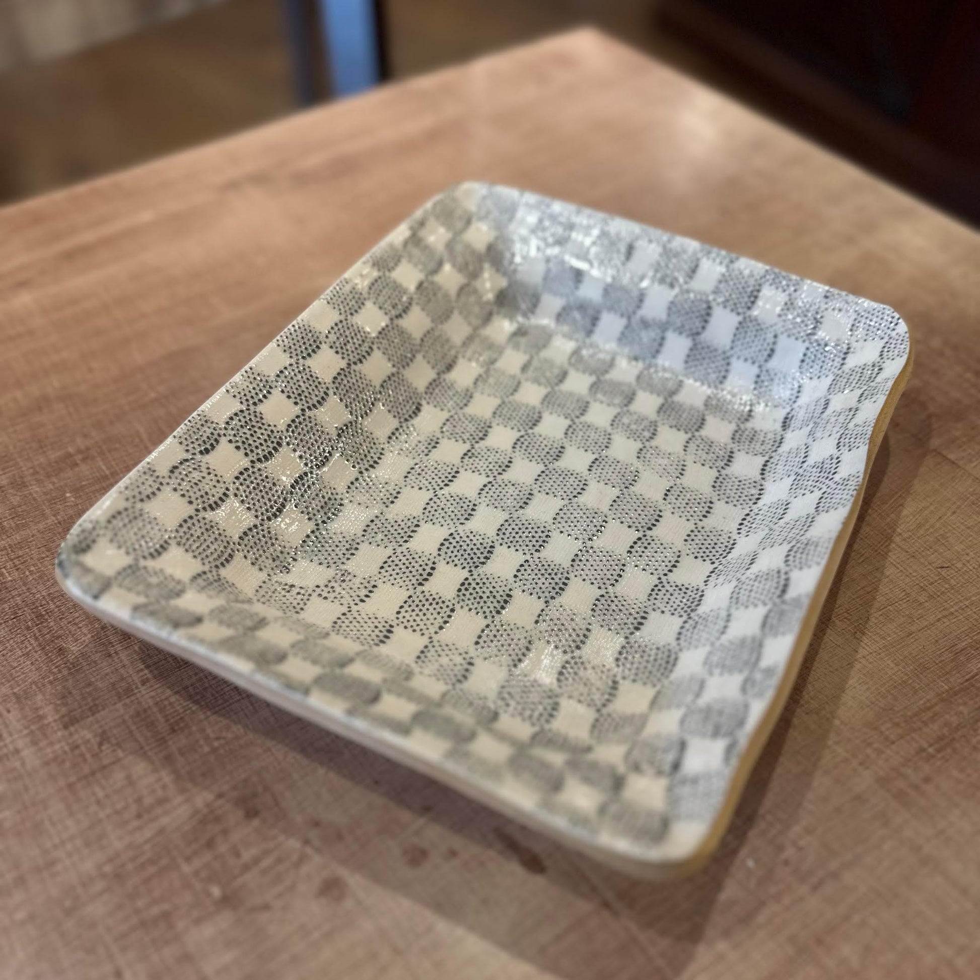 Rectangular ceramic dish with a checkered pattern on a wooden surface