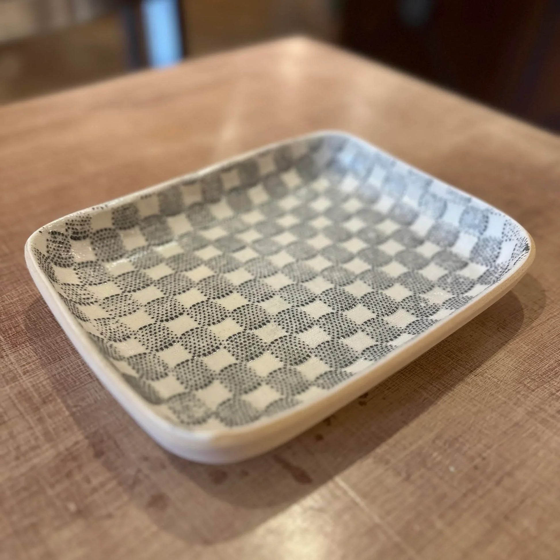 Rectangular ceramic dish with checkered pattern on a wooden surface