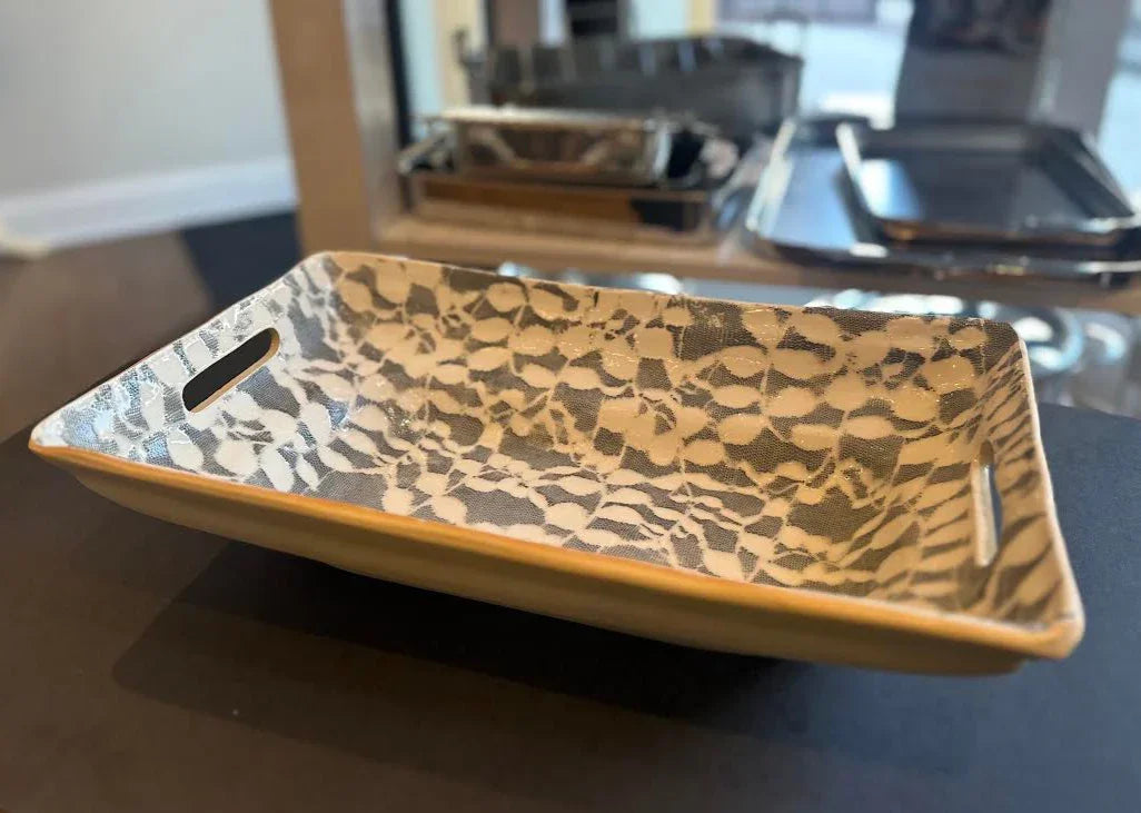Decorative ceramic tray with a geometric pattern on a glass table