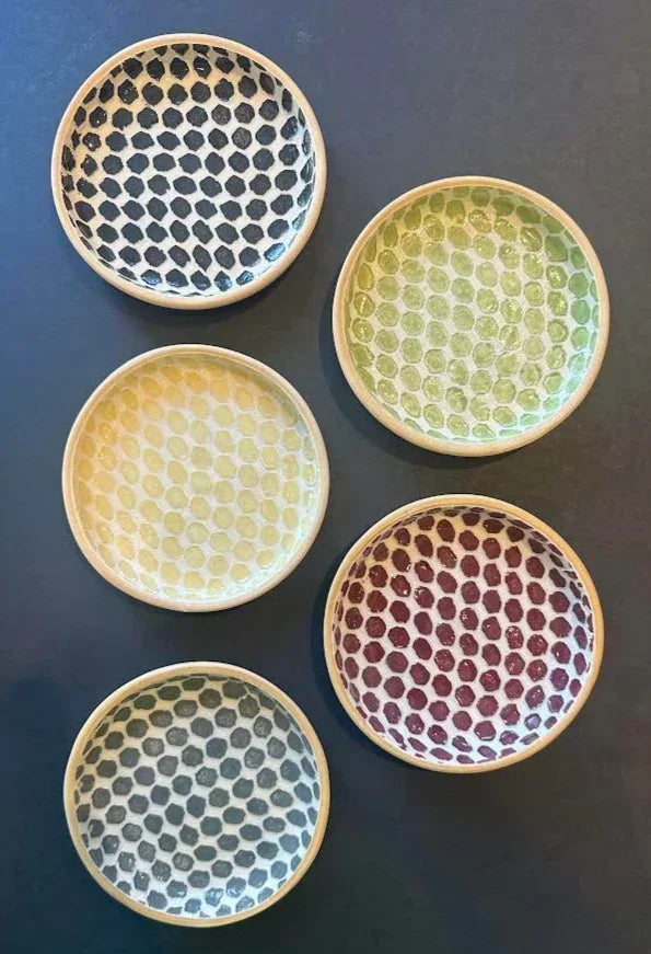 Set of five colorful ceramic coasters with honeycomb patterns on a dark background